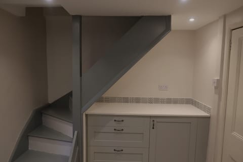 Kitchen with fridge and freezer box, narrow stairs to floor above