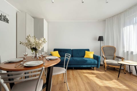A bright, cosy living room with a place to relax on a navy blue sofa and a dining area with elegant tableware.