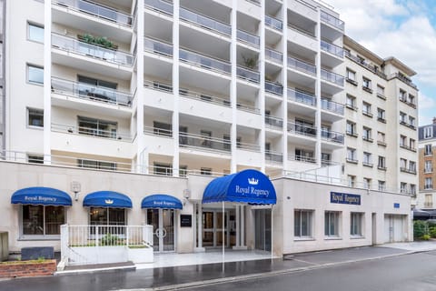 The elegant façade of Royal Regency Hotel, with its stylish exterior with balconies and signature blue canopies welcoming you to a luxurious stay.