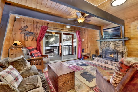 Cozy mountain living room with a stone fireplace, comfy seating, and smart TV—perfect for relaxing evenings, movie nights, and warm cabin vibes after outdoor adventures.