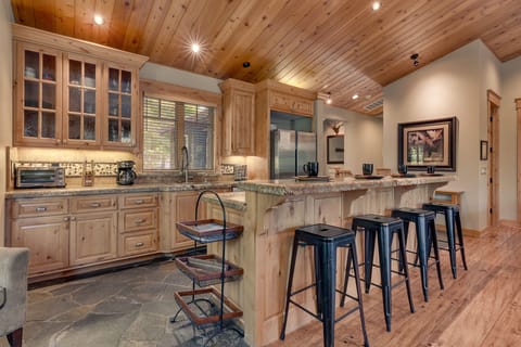 - Rustic wood cabinetry and granite counters in kitchen  
- Open-concept design with breakfast bar seating  
- Tahoe cabin rental with well-equipped kitchen space