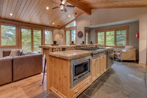 - Kitchen island with stove and modern appliances  
- Forest views from open windows and vaulted ceiling  
- Mountain vacation rental perfect for cooking together