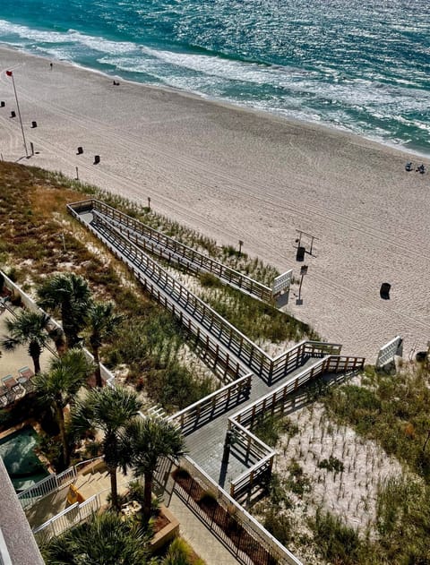 Pristine sandy beach with turquoise waters and wooden boardwalk providing direct access to the coastline.