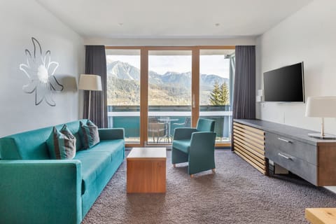 This cozy 1-bedroom apartment in Schladming features a spacious living area with two single beds, a smart TV, and a fully equipped kitchen, complemented by a balcony offering breathtaking views of the surrounding mountains and forests.