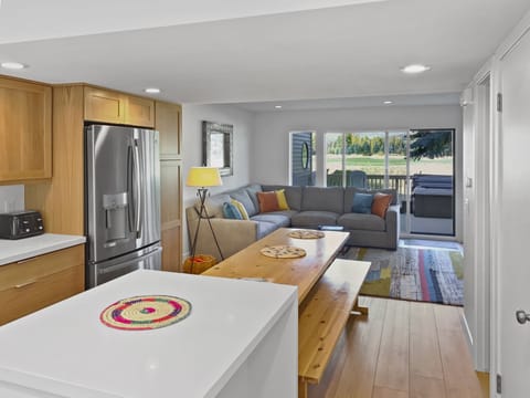 Gather in our open-concept living area featuring a full kitchen with stainless steel appliances, a comfortable sectional, and a unique rustic dining table with benches.