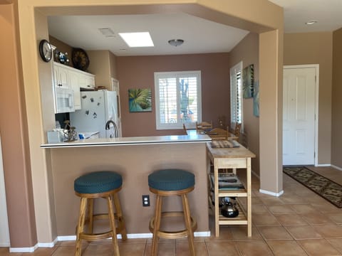 View into eat in kitchen with serving bar and comfy seating.