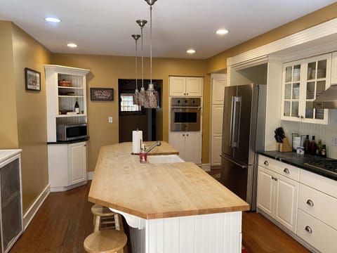 Large kitchen with butcher block counters, farm sink, gas stove, and fridge. 