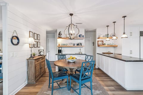 You'll love preparing meals in this bright coastal kitchen with its charming shiplap walls, granite counters, and cheerful blue dining chairs.