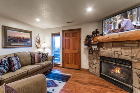 Warm up in the cozy living room with a rustic stone fireplace, comfy seating, and a flat-screen TV. The perfect spot to gather, unwind, and enjoy the mountain lodge ambiance after a day of adventure.