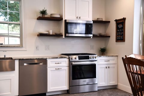Bright kitchen includes full range, microwave, farmhouse sink