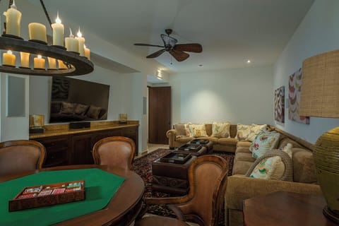 The game and television room at Casa Cielo at Pedregal, with a green baize card table, leather seating and a wrought-iron chandelier.