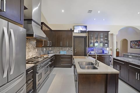 Chef's kitchen w/ island an 10 person bar counter. Door under TV leads to garage