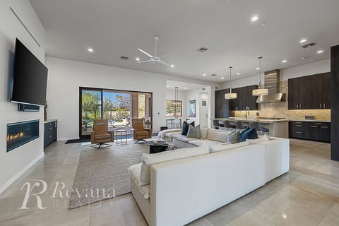 Open living area with comfy seating, large TV, and a sleek kitchen island