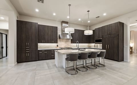 Chef’s kitchen w/ custom cabinets, quartz counters, pendant lights, & storage.