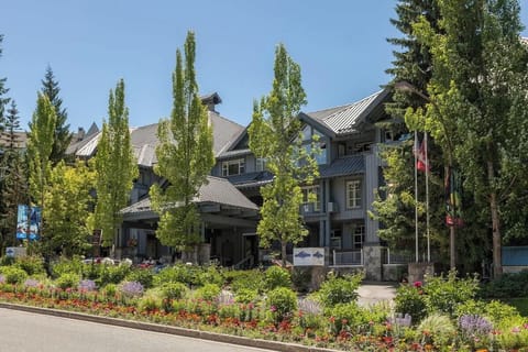 - Welcoming resort exterior with lush greenery and flags  
- Just steps from Whistler Village’s shops and restaurants  
- Perfect alpine base with vibrant landscaping all around  
