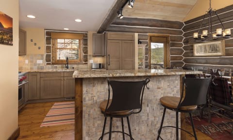 Your rustic kitchen features granite counters, bar seating, and exposed beams creating a cozy mountain retreat atmosphere.