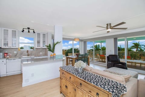 Bright, open living room with a smart TV, ceiling fan, mini-split AC, and comfortable seating for the whole group — Gulf views and natural light pour in through the large windows.