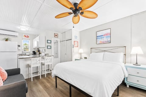 Bright studio space with a queen bed, TV, ceiling fan, mini-split AC, and a twin sofa bed for additional sleeping — a cheerful, airy retreat just steps from the sand.