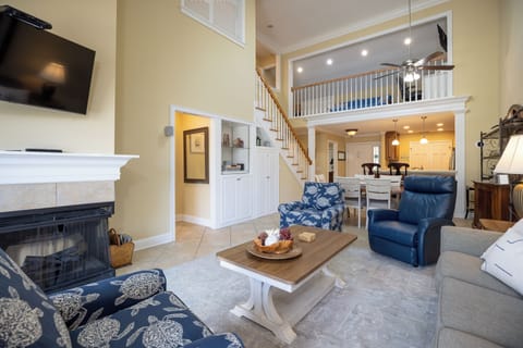 This inviting living space features soaring ceilings and an open, airy layout that seamlessly connects the living, dining, and kitchen areas.