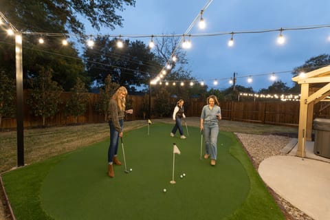 Private backyard putting green under café lights.