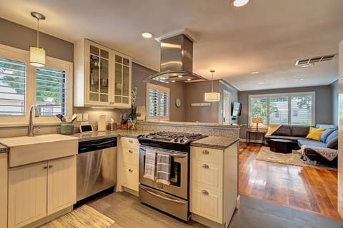 Modern, open concept kitchen with granite countertops, stainless appliances, farmhouse sink, coffee bar and a gas range.