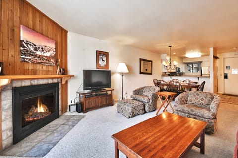 Living room with gas fireplace has wood paneling and tile surround to relax around after a day of skiing.