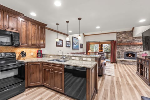 Your spacious kitchen features granite countertops, rich wood cabinets, and a cozy stone fireplace.