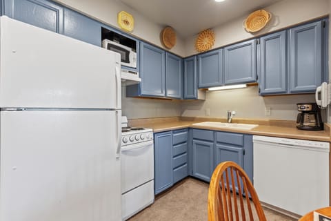 Snow Flower 72's kitchen with blue cabinets and white appliances.