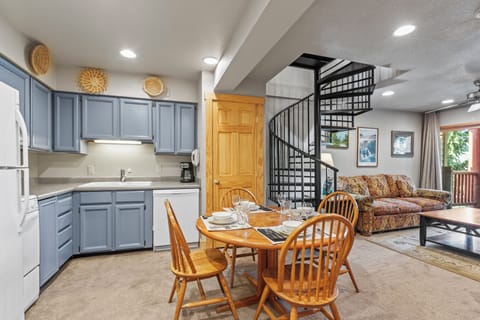Snow Flower 72's kitchen with blue cabinets and white appliances and open to living room and a black spiral stair case.