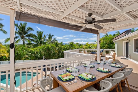 Enjoy alfresco meals in this shaded outdoor dining space overlooking lush greenery and palm trees