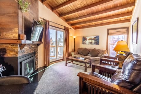 Unwind by your crackling fireplace in this cozy alpine living room with exposed beams and mountain views from your private balcony.
