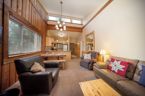 Unwind in your spacious living room with vaulted ceilings, cozy leather seating, and warm wood accents creating the perfect mountain retreat atmosphere.