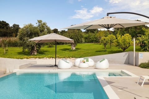 View of the private swimming pool and the lounge sofas and parasol on the outdoor terrace in the luxury family villa Deluxe Pula in Croatia