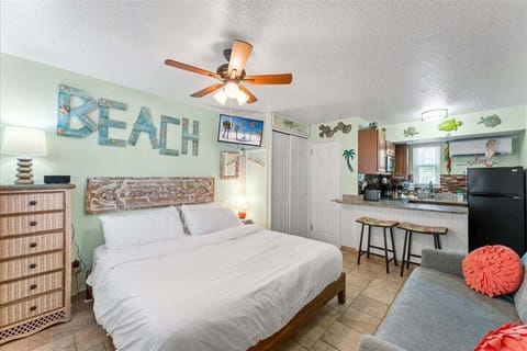 Bright studio suite with a king bed, coastal décor, and a fully equipped kitchen — a cheerful, beachy space where everything you need is right at hand.