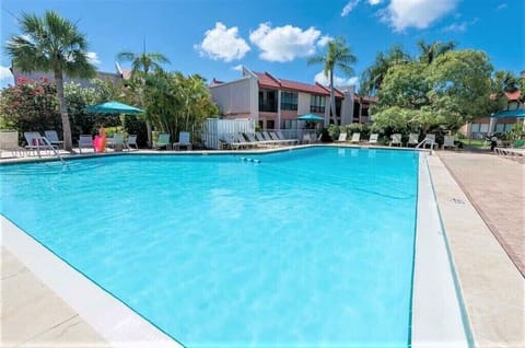 Large resort-style heated community pool with pool deck and tropical landscaping