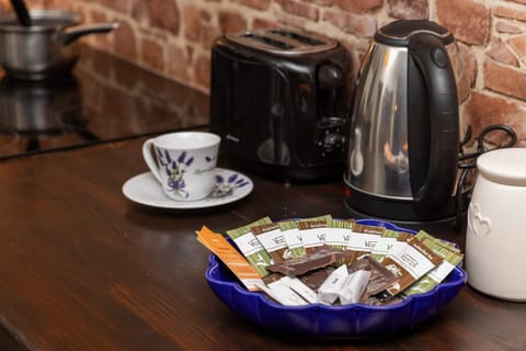 A close-up of a countertop with kettle, and a bowl with coffee pods and tea bags, ready for guests.