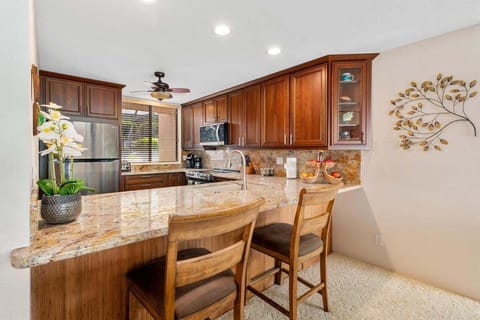 Full kitchen with view out to the lanai, golf course  and ocean beyond.