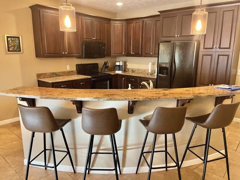 Fully stocked kitchen with granite countertops and bar seating for four people