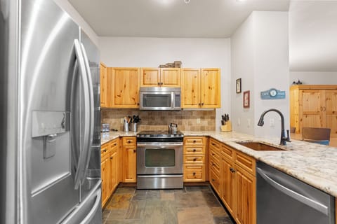 Full kitchen with stainless steel appliances and breakfast bar seating.