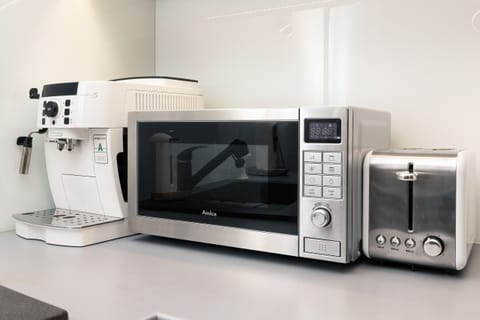 A kitchen corner with a microwave, coffee machine, and other appliances, perfect for quick meals.