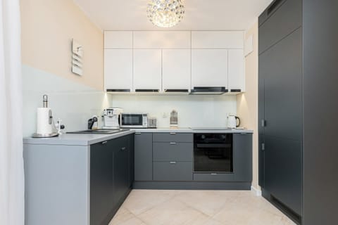 A fully equipped kitchen with dark cabinets, light countertops, and modern appliances.