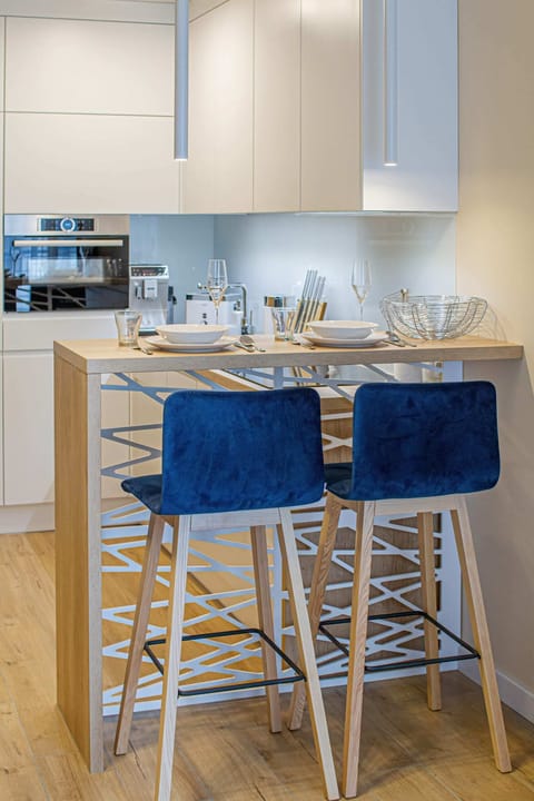 A contemporary kitchen with white cabinetry, a sleek breakfast bar, and vibrant blue bar stools, creating a refreshing space to cook and dine.