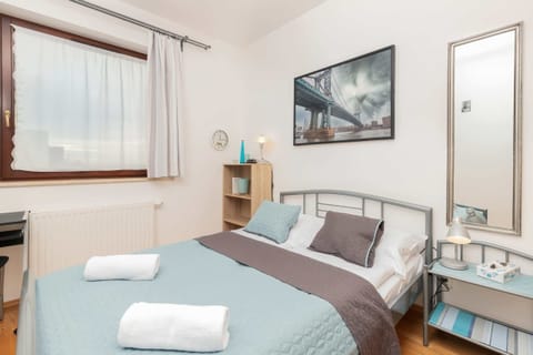A bedroom with a neatly made bed, bedside tables, and a framed picture on the wall. The space is cozy and functional.