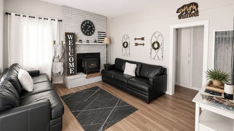 Cozy living room with wood stove, leather sofas, and natural light.