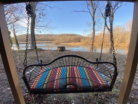 Porch swing below facing river with fire pit 