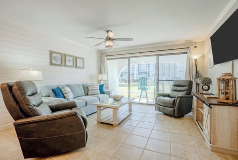 Spacious living area with sleeper sofa and two recliners, ceiling fan, smart TV and patio access