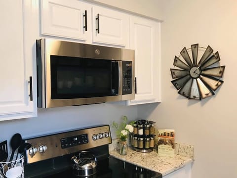 Stove and microwave, tea kettle and cooking spices.