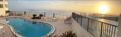 Pool with beach view, shower, and tanning deck