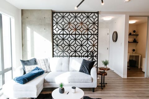 Bask in the sunshine-filled living room, perfect for lounging on the cozy sectional. Enjoy the view of the serene plant on the coffee table or grab a book from the nearby shelf to settle into your space.
