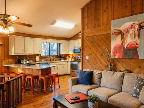 Warm wood tones, cozy seating, and a kitchen made for gathering—this is where mountain mornings start and memories are made with a stunning cow picture painted by our niece!